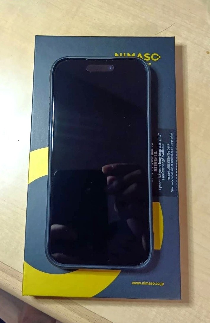 NIMASOの覗き見防止ガラスフィルムのパッケージの上に、フィルムを貼ったiPhone 15 Proを置いた状態